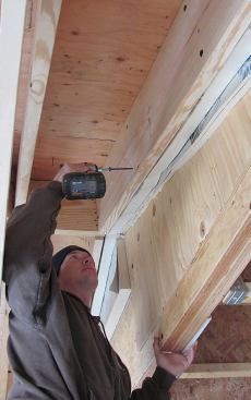 Structural screws driven through the foam tie the isolated frames together. Here, the author anchors a walk-out bay rafter to the wall framing.