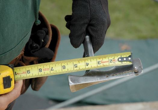 The author uses the gauge button on the shingling hatchet to lay out courses. The hatchet comes with buttonholes every 1/2 inch; he heats the blade and uses a drill press to make additional holes at 1/4-inch increments, which is enough to handle any spacing variations.
