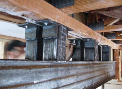 Pairs of steel cripples welded between steel channels support the fire wall's two top plates and the roof trusses overhead.