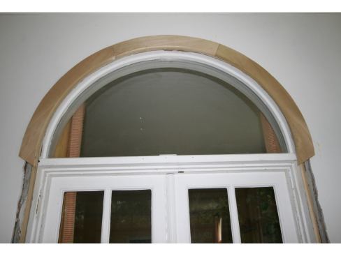Installing the curved molding at the doors was tricky. As it turned out, the radius was not true, so we cut three pieces of wide, poplar stock close with a jigsaw and then installed it and used a flush cutting bit on a router to follow the irregular radius.