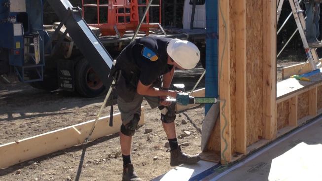 A crew member applies sealant to the “marriage plate” at the end of a wall panel in preparation for setting the adjacent panel. Sealant at panel intersections is a key element in the air-tight performance of the Passive House package.