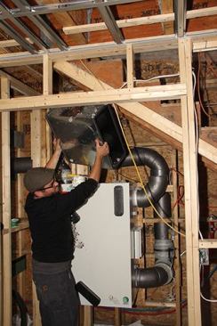 Travis Anderson places a distribution manifold manufactured by Zehnder on top of the Air Pohoda ERV unit. The designers combined components from Zehnder and Air Pohoda for this installation.