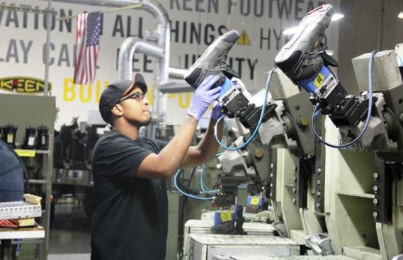 A worker attaches lasts and boot uppers to the Desma machine. The machine will form the midsole that joins the upper to the outsole (sole) by injecting a two-part polyurethane material between and around the pieces.
