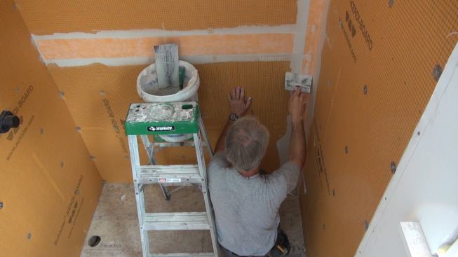 Boucher works the Kerdi-Band into the mortar with his customized spackle knife.