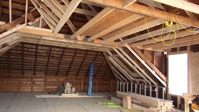 Another view of the second-floor space with new site-built structural trusses installed, collar ties and new ceilings framed in, and the roof build-down mostly completed. A new dormer still remains to be built at the back of the house.