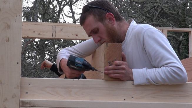 Not wanting to take a chance on splitting the end of the expensive lumber, Hill drills a pilot hole in the outboard end of the Doug Fir joist. The cut ends of the joists, graded Select Structural, show 15 to 30 annual growth rings.
