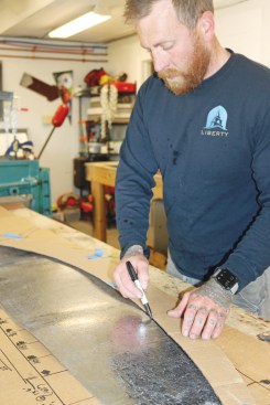 Kyle Ouellette begins the metal work for the roof by tracing the curve for the rake edge on a sheet of lead-coated copper.