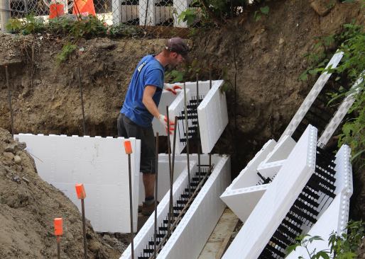 Steve Daly sets a corner form section for the ICF foundation system. The recommended process is to start setting foam form blocks in the corners and work toward a point in the center of the wall.