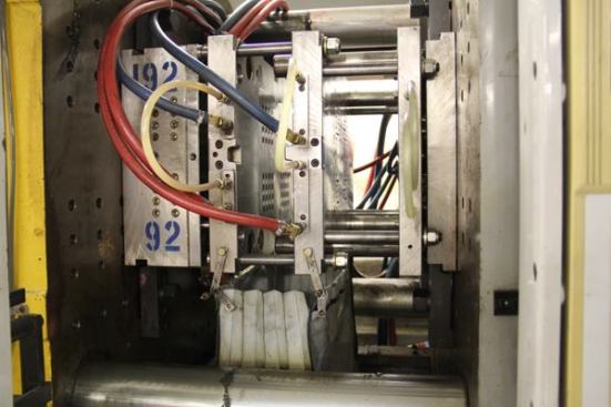 The vertical metal plates shown here are an injection mold, the “business end” of an injection molding machine. The machine brings the molds together, injects molten plastic, the plastic cools and solidifies, the molds come apart, and the plastic pieces fall out and are blown into a bag. 
Click here for video.
