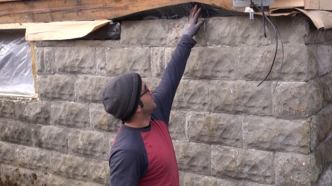Project manager Mark Pollard points out where his crew has placed a Grace membrane capillary break between the old home’s existing block foundation and its existing sill beam in this photo from December, before severe weather struck New England. The crew is now tying this membrane into an air barrier membrane for the home’s walls as part of detailing the building’s new airtight and insulated exterior weather barrier.