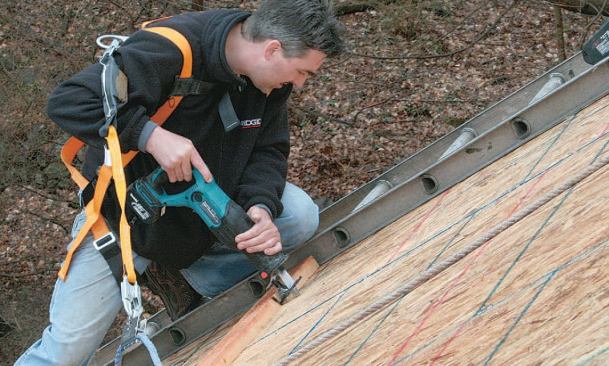 The solar installer uses a recip saw to cut one of the penetrations needed for the fluid pipe loop between the collectors and the utility room.
