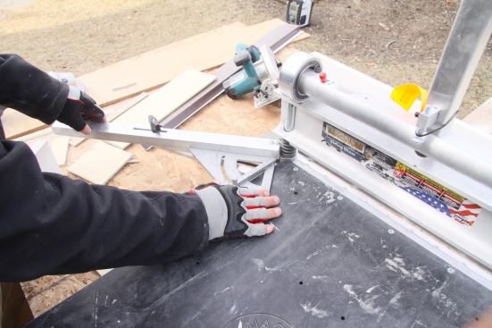 An aluminum fence on both sides of the shear allows for fine-tuning the angle cut. Here, a bevel square sets the angle and a thumb screw locks it into postion.