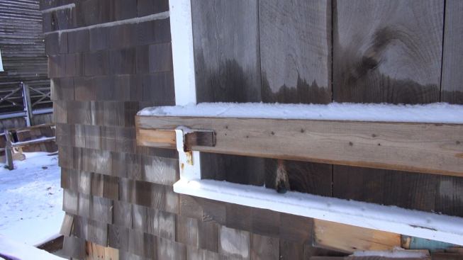 A closer look at the metal bracket that holds a shimmed 2x6 bar in place to secure the storm shutters.