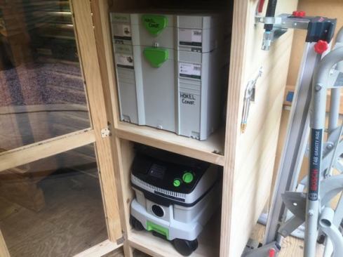 A tall narrow cabinet at the right rear end of the trailer houses a Festool dust extractor, track saw, and a Systainer filled with accessories.