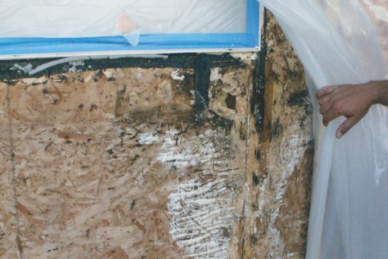 Less than ten years old, this building had been repaired twice previously with surface-sealing methods that did not work. The author's crew first stripped the stucco. At this window corner, badly detailed flashing and paper let water soak the sheathing and framing, leading to rot.
