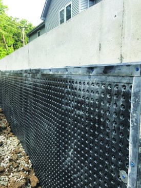 A bitumen coating needs a dimple mat in front of it to relieve hydrostatic pressure. The dimples create a space between the soil and the concrete, allowing water to drain freely to footing drains.