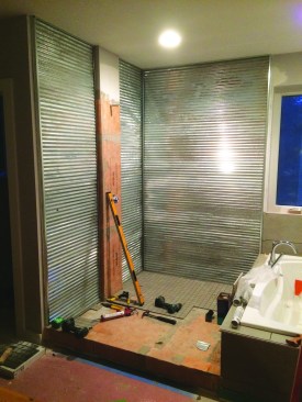 Wood battens provide drainage space, and custom-bent metal channel is used to trim out the edges of the corrugated panels. The panels are secured to the battens with grommeted screws, as they would be on an exterior. If the fasteners leak, well, there’s a rainscreen.