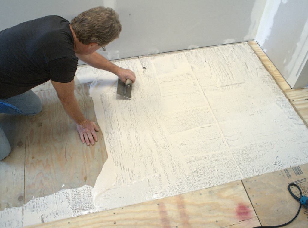 To achieve maximum strength and smoothness, 95 percent to 100 percent of the entire plywood surface must be covered with ANSI Type 1 or 2 waterresistant wood glue. At the perimeter of the floor, to avoid squeeze-over into the movement-joint slot, the author keeps the glue about 1/2 inch from the wall.