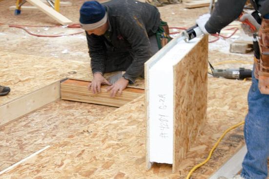 A built-up LVL header, sized to carry the load from the beam, is slipped into the panel above the window opening.