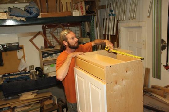 In the cabinet shop, Jeff checks the dimensions of a custom base cabinet before starting to build the toe-kick base for it.