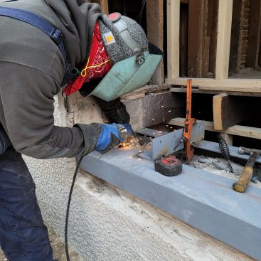 A welder then begins attaching angle-iron cross braces.