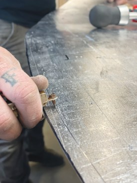 After cutting the curve with snips, he scores the metal to define the hem.