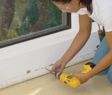 To protect low windows in areas where an existing floor will be demolished, the baseboards are removed and a series of screws are driven into the wall just below the height of the eventual replacement base.