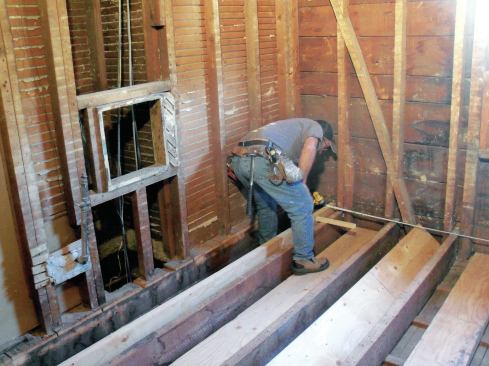 I began the installation in the highest corner. Pulling the layout from the opposite wall, I locked the first new joist in position with a scrap screwed to the nearest old joist.