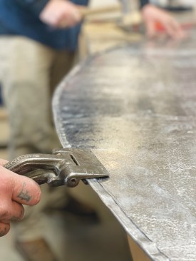 He then folds the hem over with tongs.