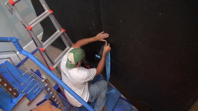 The crew seals joints in the sound-deadening vinyl using a 1/16th-inch tape made of the same material, with a polyvinyl acetate (PVA) adhesive. Sealing the joints is critical to the performance of the system: it prevents sound from bypassing the sound-absorbing material through air gaps between the sheets.