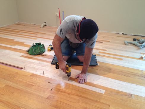 Because the last boards to go in are not fully engaged with the adjacent boards, Manny predrills and screws them in through their faces. The holes will be filled before the floor is sanded and finished.