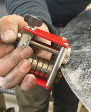 With a roller bender, he rolls the edge over at an angle to form a drip edge.