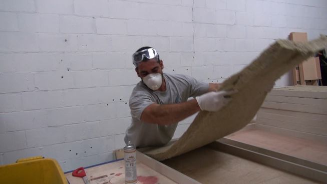 Installing sound-absorbing rock wool fiber insulation into the panel. The insulation comes in one-inch, two-inch, and three-inch thicknesses. Thicker insulation is better at absorbing low frequencies of sound, while thinner insulation is more effective with higher frequencies. Drago typically uses a two-inch thickness to optimize sound absorption across the broadest frequency range.