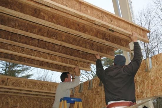 Previously installed joist hangers receive the I-joist ends as the floor sections drop into position.