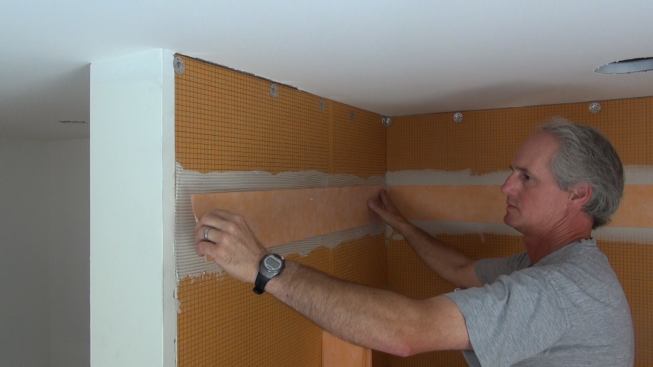 Boucher sets a strip of Kerdi-Band waterproofing membrane over the prepared joint.