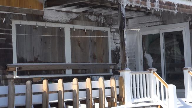 Wooden storm shutters hung from metal hardware and dogged down with a 2x6 bar protected Hackett’s first-story windows from crashing waves during the blizzard. Wind-driven spray and snow coated the underside of the porch roof.
