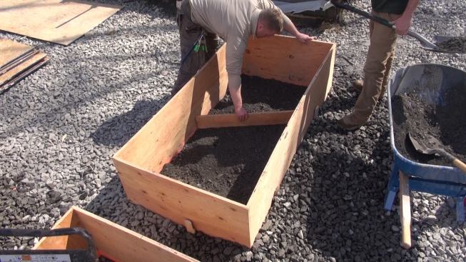 Tim screeds the crusher run layer smooth and level with a scrap of plywood.