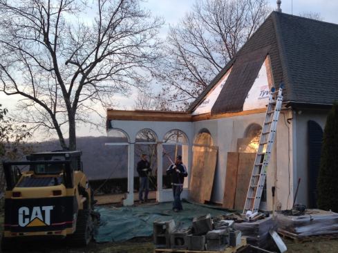 Then we turned to the porch walls, which were stucco-clad. The posts and top portion around the existing half-round windows were wood-framed, with short block “knee walls” at the base. We pulled them down with the help of a skid-steer, which we also used to remove the top courses of the existing block frost wall and slab, and to help clean up the debris.