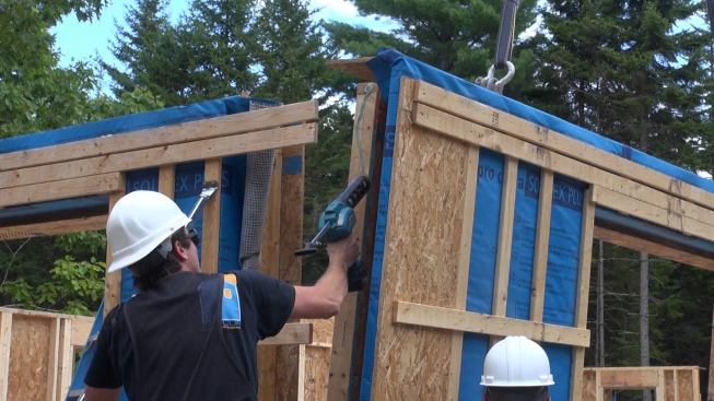 Applying more adhesive sealant to the end of a wall panel before setting the panel into place. The air barrier layer for the Passive House wall system is located at the sheathing plane of the inner stud wall in the system. Where studs in that wall system meet floors or other wall studs, sealant has to be used to complete the air-tight layer.