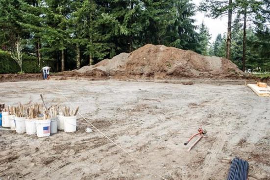 When laying out the footings, the author determines diagonal measurements using the rise/run function on his construction calculator, then refers to those measurements to verify that corners are square. The stretched string on the right-hand side of the photo indicates the outside edge of the first set of footings.