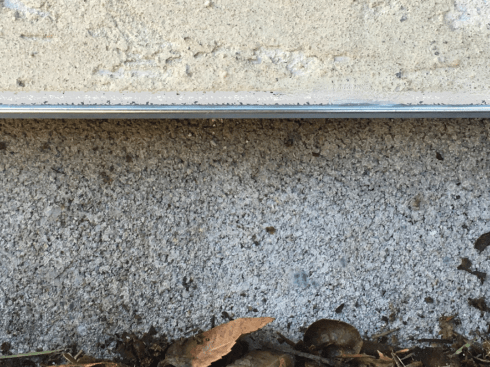Above is a grade-level view of plywood and stucco with weep screed overhanging a slab footing. Looks tight, right?