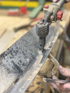 After using a lock seam to join the drip edge to a second strip of metal, he reinforces the lock seam with solder from the back.