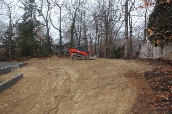With the smoothing and scraping finished, the grade behind the house meets the existing grade in a gentle slope and eliminates the need for an expensive retaining wall.