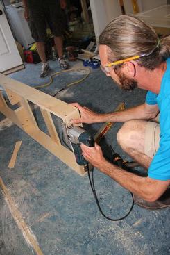 With a jigsaw, Jeff trims the back of the box so that it will lay flat and level against the sagging, out-of-level existing kitchen floor.