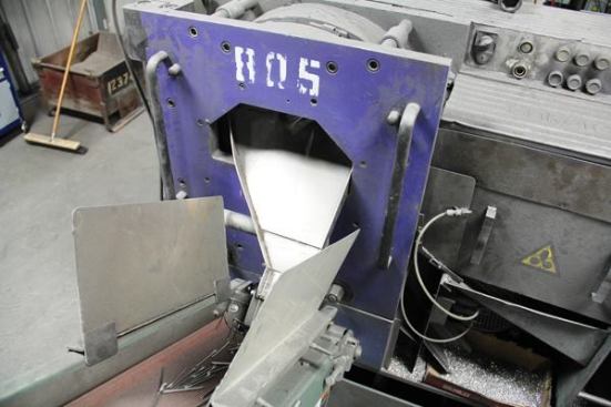Nails fall onto a conveyor at the outfeed side of the nail making machine and are conveyed to the hopper of a rotary orienting feeder, a device that positions them for processing by the next machine. 
Click here for video.