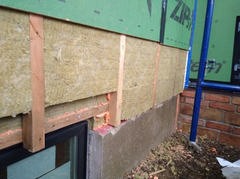 A peek under the Zip sheathing reveals a double layer of 2-inch-thick Rockwool Comfortboard 80, for a total of R-16. We used this strategy in areas we did not have access to from the interior. We used foam sealant in any gaps between the Comfortboards to eliminate interstitial convection within the cavity insulation.