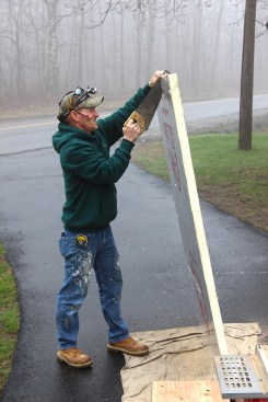 He cuts out foam insulation for the door, using a handsaw.