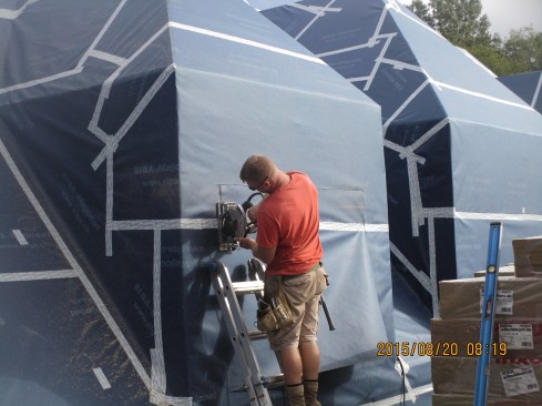 Carpenter Tim Houldcroft cuts out a window opening in the membrane-covered wall.