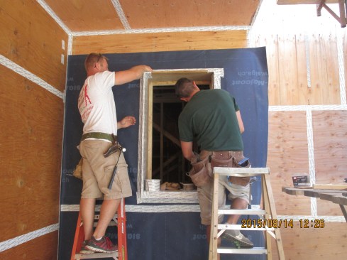 Carpenters Tim and Casey work on a window opening prototype in the Passive House wall.