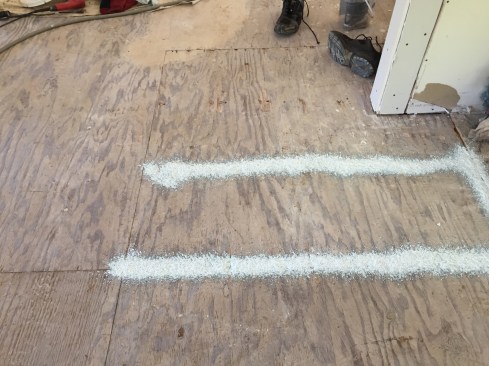 Leaks through a plywood subfloor with gaps and holes also pulled crawlspace air inside. Here in the living room, where the floor is to be covered with carpet, we applied a flexible, airtight coating, 1mm to 2mm (one to two dimes) thick. This took about five to six seconds per foot.